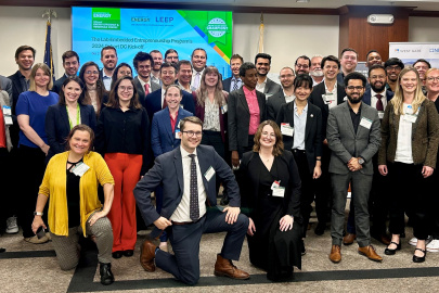 A large group of people in an office setting pose for the camera. 